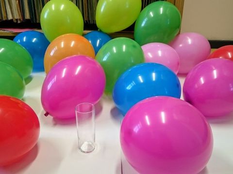Ein Trinkglas umgeben von 17 Luftballons