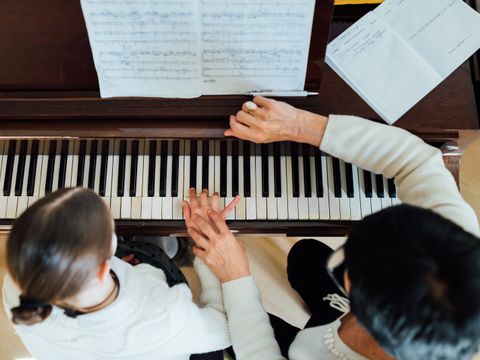 Musiklehrerin hilft Schülerin beim Klavier spielen