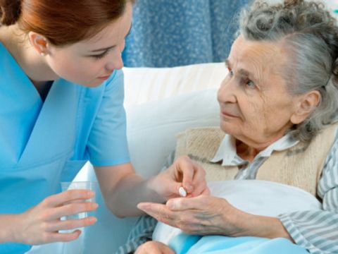 Krankenschwester kümmert sich um eine ältere Frau im Bett liegend