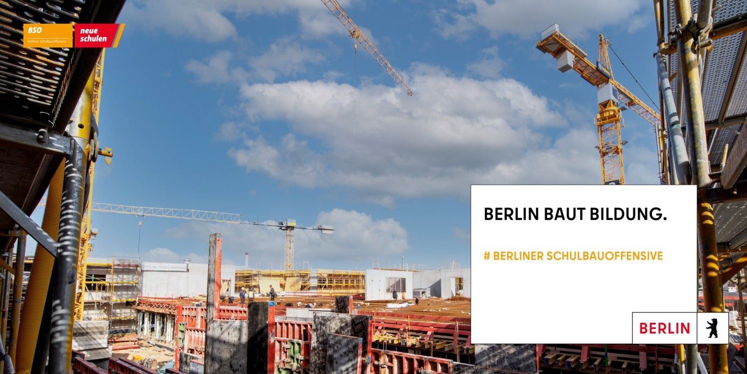 Blick von oben vom Baugerüst auf eine Baustelle mit Kränen und im Vordergrund rechts ein Feld in dem "Berlin baut Bildung" steht