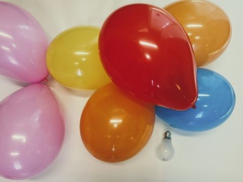 Eine Glühbirne umgeben von 7 bunten Luftballons