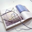 Bildvergrößerung: aufgeschlagenes Buch mit der Abbildung einer Skulptur, darauf befinden sich Elektrokabel, die wie eine Verlängerung der Skulptur wirken