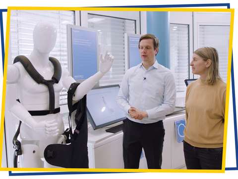 Ein Mannequin, ausgestattet mit Tech-Gegenständen, ein Mitarbeiter des Projekts und eine weitere Person stehen im Industrie 4.0 Labor.
