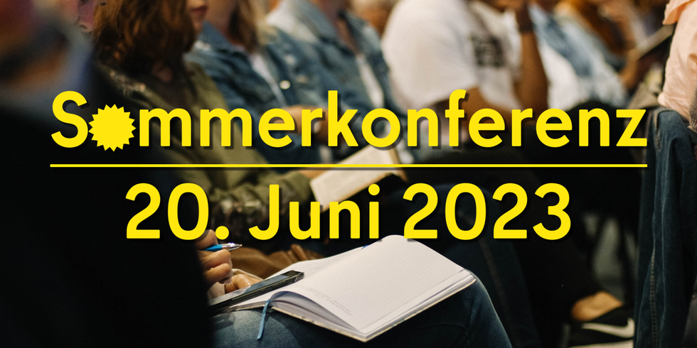 Schriftzug "Sommerkonferenz 20. Juni 2023" vor dem Publikum einer Veranstaltung