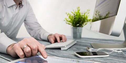Mann bedient Tablet und Tastatur eines Computers gleichzeitig