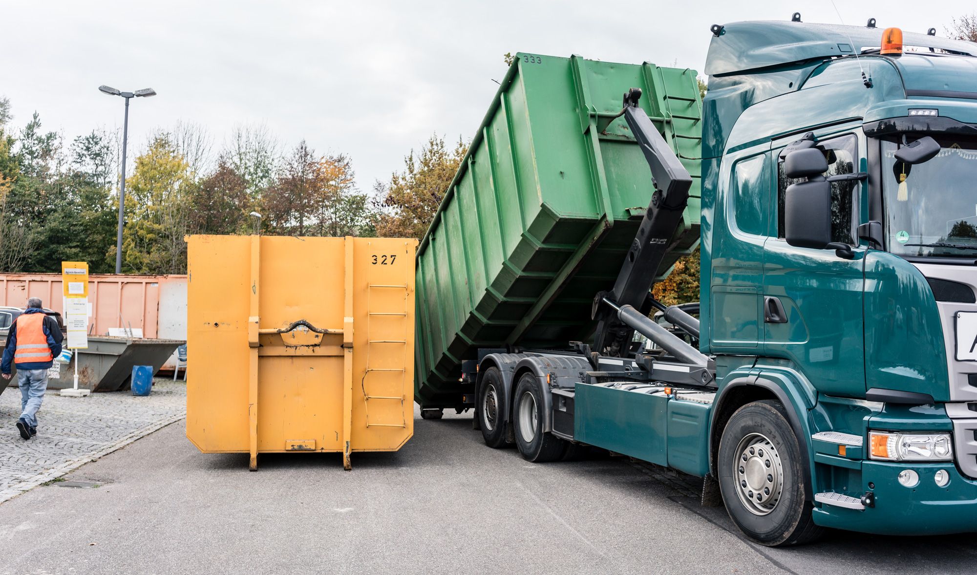 Lkw belädt Container mit Abfall im Recyclinghof