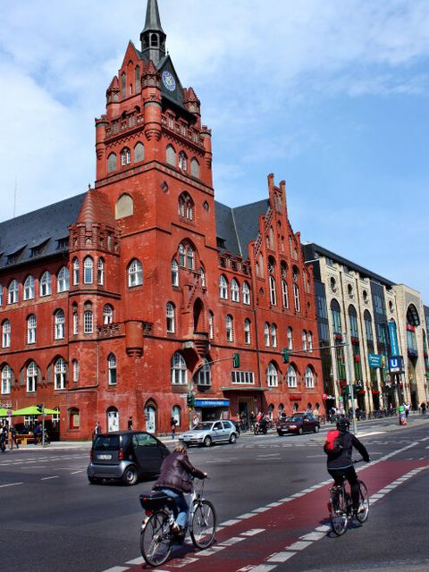 Zwei Radfahrer fahren auf dem rot markierten Fahrradstreifen gegenüber des Rathauses Steglitz die Schloßstraße in Richtung Norden.