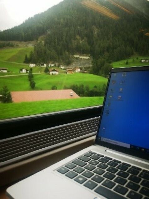 Laptop im Zug mit Landschaft im Hintergrund
