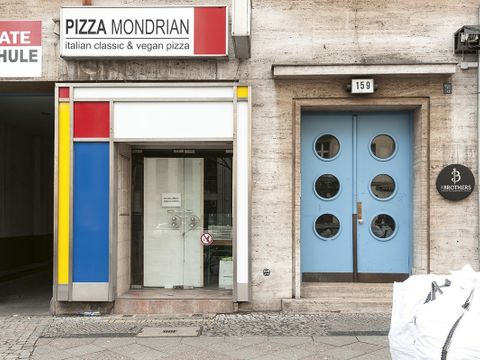 Bildvergrößerung: Die Fassade eines bunten Geschäftes. Über dem Eingang steht "Pizza Mondrian".