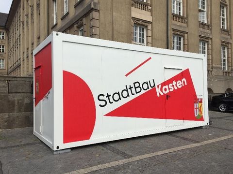Bildvergrößerung: Ein rot-weißer Container mit dem Schriftzug: StadtBauKasten steht vor dem rathaus Schöneberg.