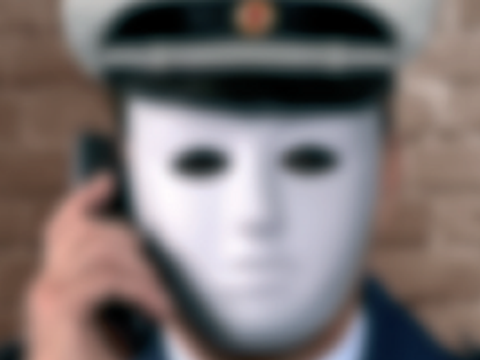 Polizist mit Maske und Telefon am Ohr, Kasten mit Text Achtung hier spricht nicht die Polizei