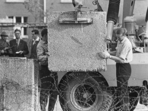 Berlin im August 1961: Aufstellen von Betonblöcken mit einem Kran hinter Stacheldraht.
