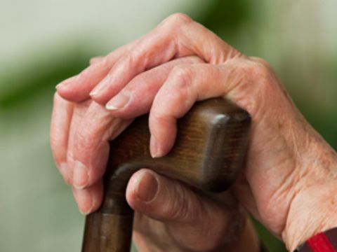 Hände einer Seniorin am Gehstock