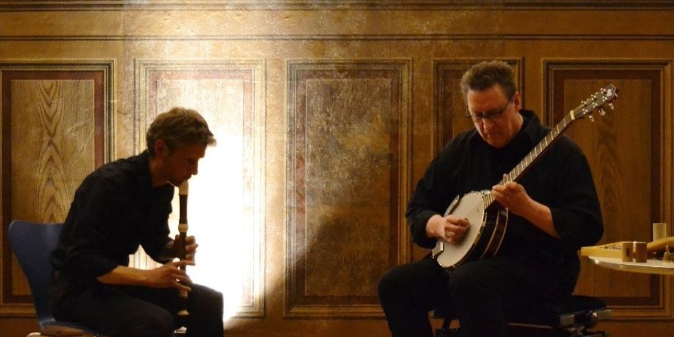 Zwei Männer sitzen auf der Bühne und spielen Flöte und Banjo