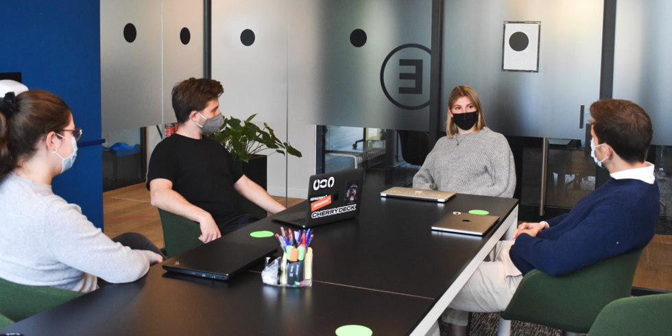 Beschäftigte sitzen mit medizinischer Maske zusammen in einem Meeting.