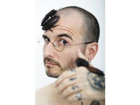 Foto eines Mannes mit Kakerlaken auf dem Kopf und auf der Hand