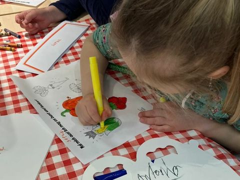 Kind malt Bilder mit Lebensmitteln bunt aus.