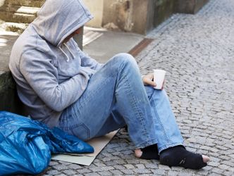 Auf Boden sitzender obdachloser Mann hofft auf Geldspende
