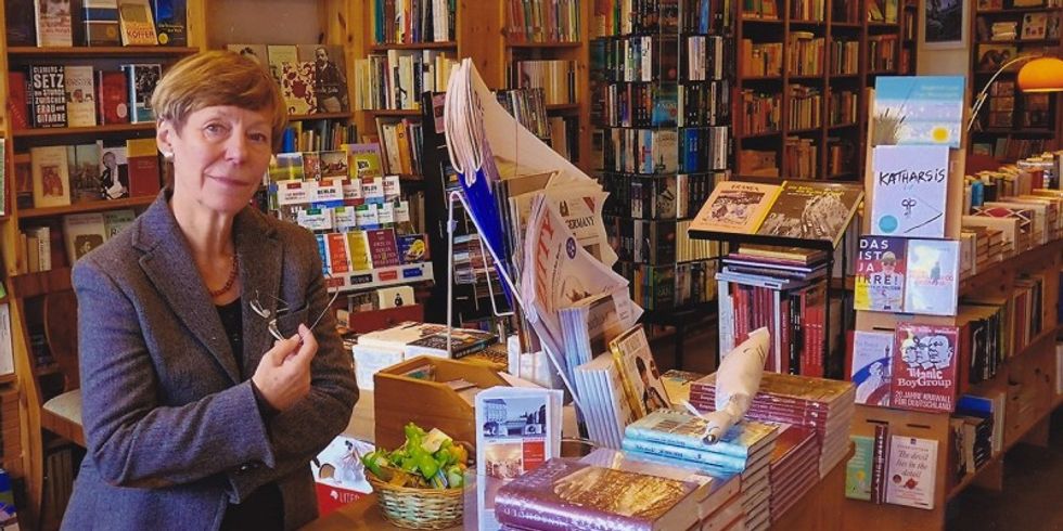 Eine Dame steht in einem Laden und um sie herum sind überall Bücher.