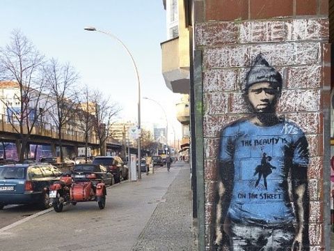 Bildvergrößerung: Neben einer Straße an einer Hauswand ist ein Grafitti, das einen Mann darstellt.