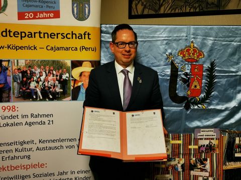 Bezirksbürgermeister hält die unterzeichnete Städtepartnerschaftsvereinbarung in seinen Händen