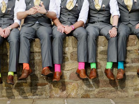 Fünf Männer sitzen auf einer Mauer und tragen bunte Socken