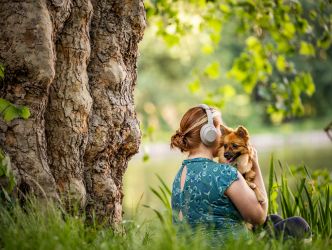 Frau mit Kopfhörern und Hund im Park