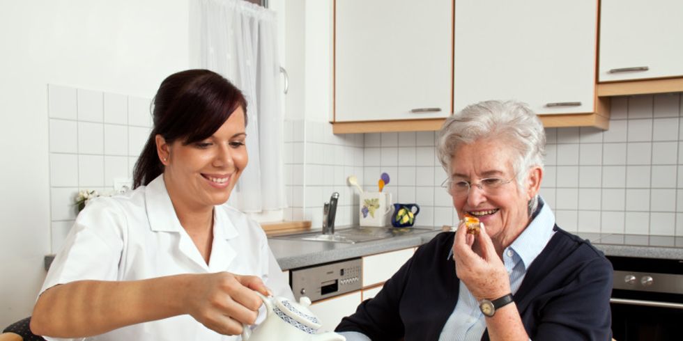 Eine Pflegerin frühstückt gemeinsam mit einer Seniorin