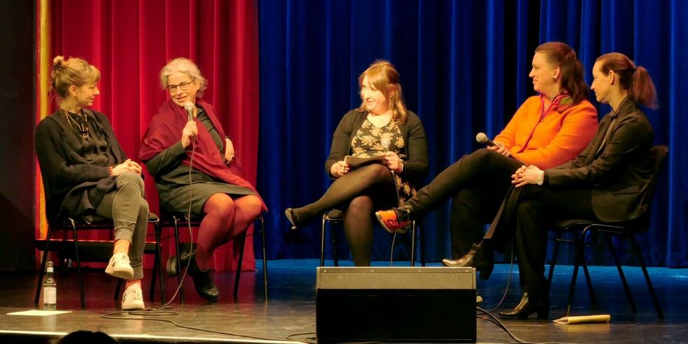 Fünf Frauen sitzen während einer Podiumsdiskussion im Gespräch auf eine Bühne.