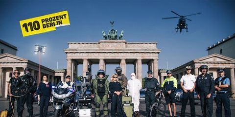 Polizisten in ihren Arbeitsbereichen vor dem Brandenburger Tor, Links oben Logo Kampagne 110 Prozent Berlin