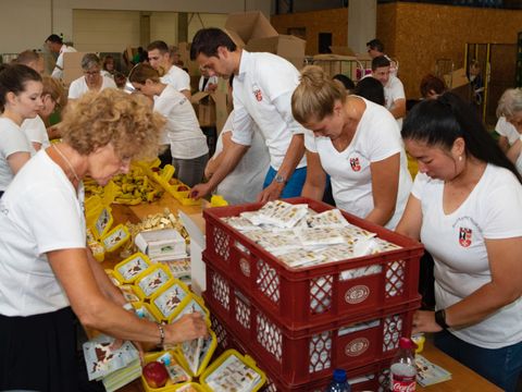 Auch Freiwillige aus dem Bezirksamt Neukölln packen mit Bezirksbürgermeister Martin Hikel die Bio-Brotboxen.