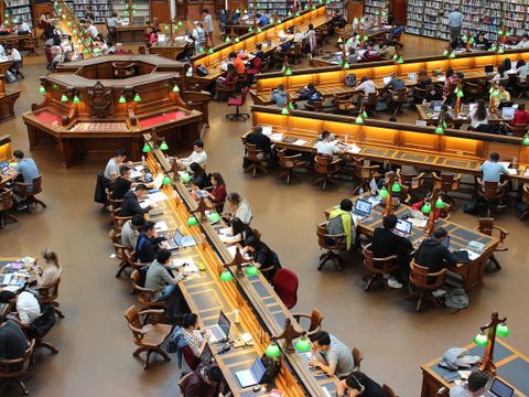 Menschen an Tischen in einer Bibliothek