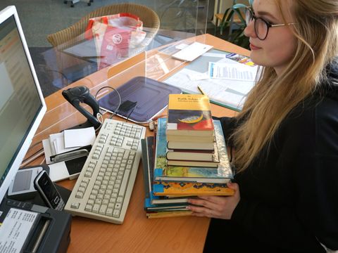 Auszubildende am Rechner- mit Büchern zur Freischaltung