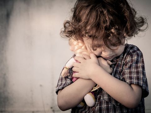 Trauriger kleiner Junge mit Puppe im Arm