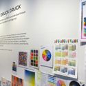 Bildvergrößerung: Wandtext der Ausstellung und verschiedene Blätter mit Darstellungen von Farbpaletten.