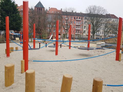 Spielplatz mit rotem Klettergerüst und blauen Seilen