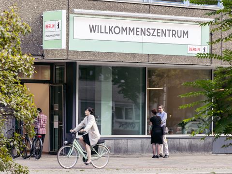 Das Willkommenszentrum befindet sich auf der Potsdamer Straße. Es stehen einige Menschen davor und eine Radfahrerin fährt vorbei.