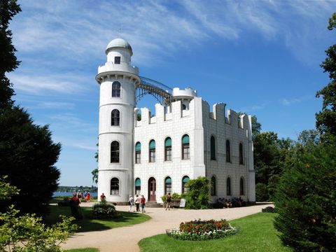 Ein weißes Prachtgebäude mit Turm, das ist das Schloss auf der Pfaueninsel