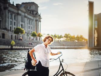Frau mit Fahrrad auf dem Weg zur Arbeit, im Hintergrund der Reichstag