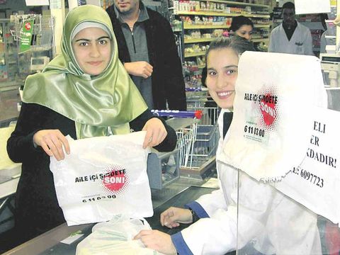 Verkäuferin zeigt die Aktionstüte mit dem türkischen Slogen Schluss mit Gewalt in der Familie