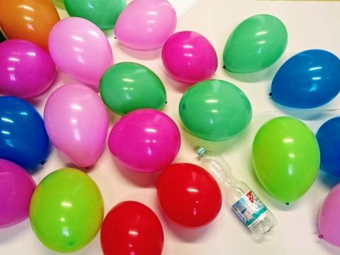 Flasche aus PET umgeben von 20 bunten Luftballons