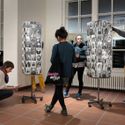 Bildvergrößerung: drei weibliche und eine männliche Person stehen vor Postkartenständern und betrachten diese