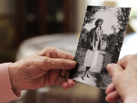 Hände einer älteren Person halten ein antikes Bild einer jungen Frau