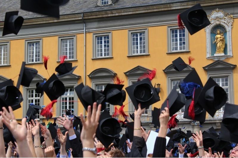 Foto einer Abschlussfeier, alle werfen Hüte in die Luft
