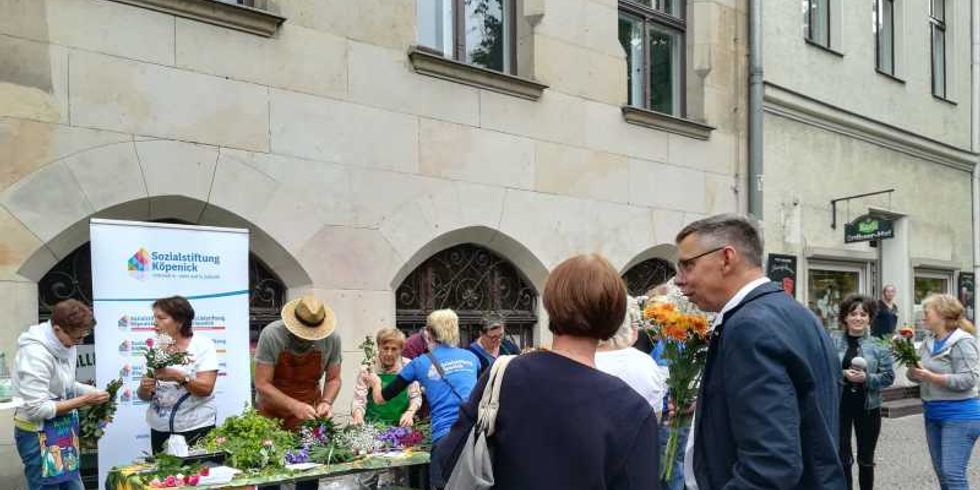 Herr Klemm übergibt selbstgebundene Blumensträuße an Passantinnen und Passanten
