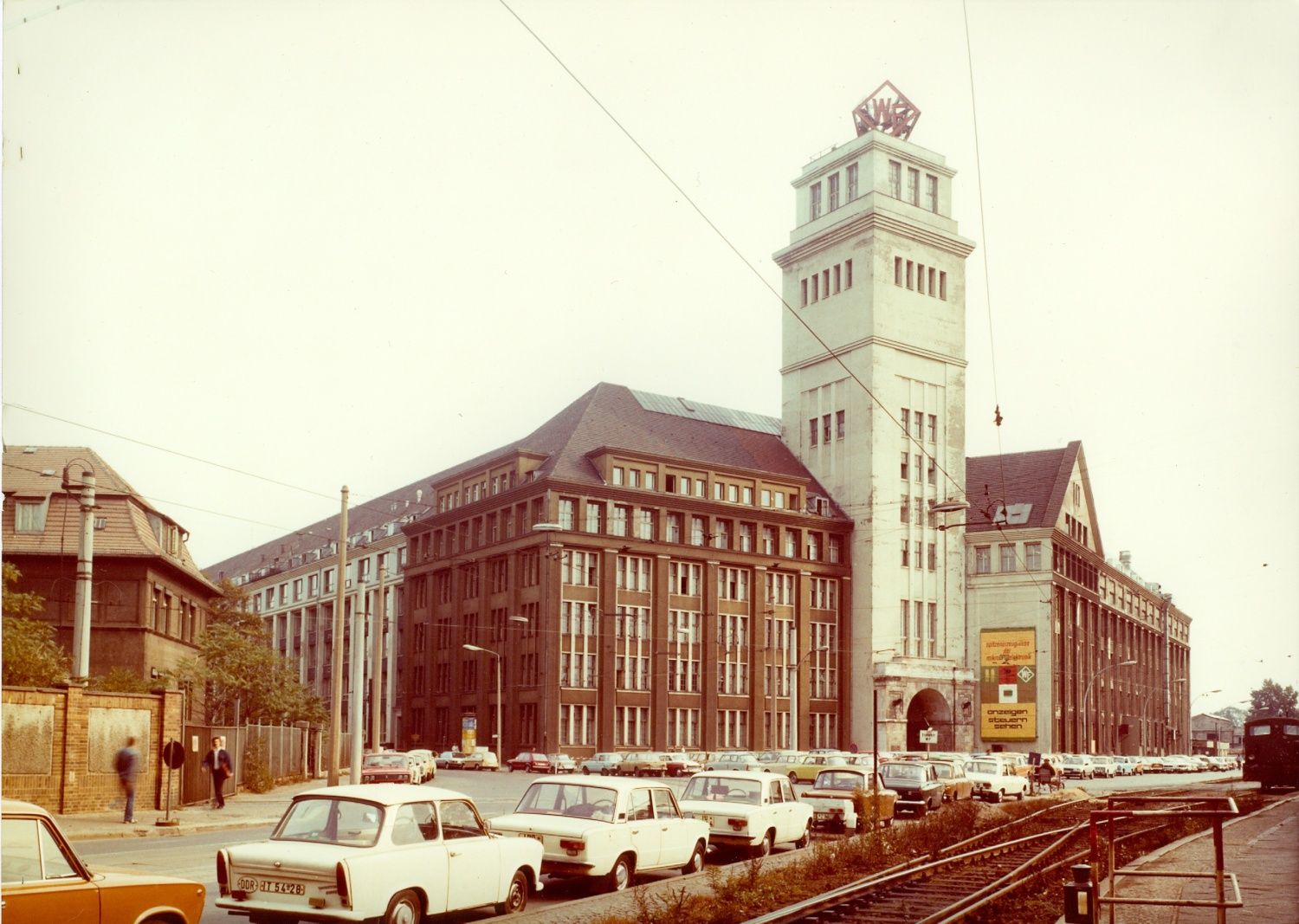 WF Turm mit Peter-Behrens-Bau, am rechten Bildrand Bahngleise, Autos im Vordergrund, Ecke Wilhelminenhofstraße-Ostendstraße