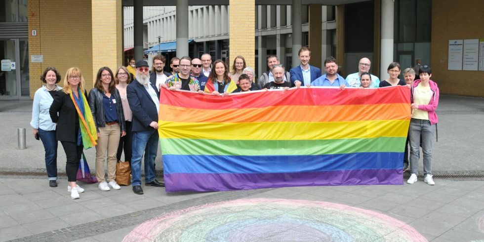 IDAHOBIT 2022 - Gruppenbild mit Regenbogenflagge, Bezirksbürgermeister, Bezirksstadträtinnen und Aktivistinnen und Aktivisten vor dem Rathaus