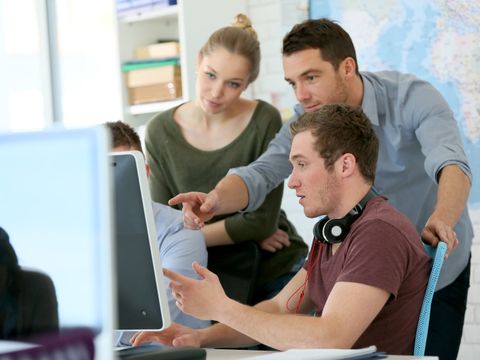 Gruppe junger Menschen arbeitet gemeinsam an einem Rechner