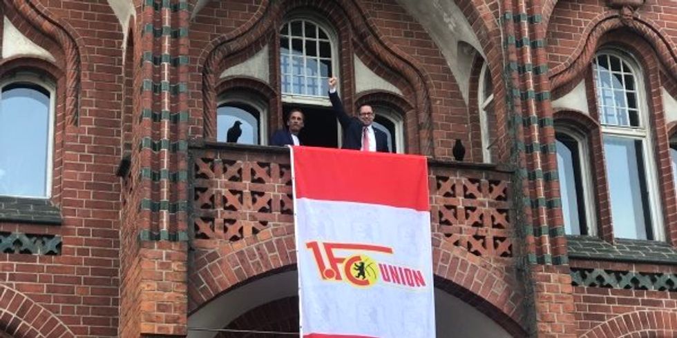 Bezirksbürgermeister Igel jubelt vom Rathausbalkon an dem die Fahne des 1. FC Union Berlin hängt