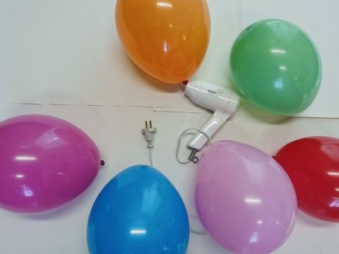 Ein weisser Fön umgeben von 6 Luftballons